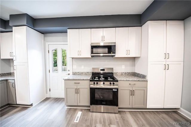 187 Lock St, Lockport-City, NY 14094 - kitchen featuring appliances with stainless steel finishes, light wood-style flooring, light stone counters, and white cabinets