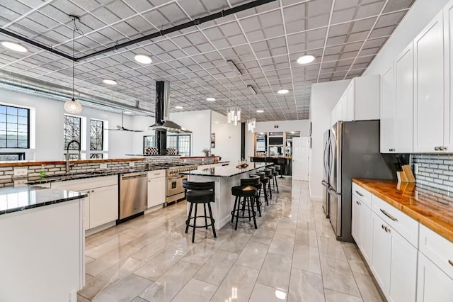 11059 Gold Seal Way, Urbana, NY 14840 - kitchen featuring stainless steel appliances, a spacious island, a breakfast bar, white cabinets, and wall chimney exhaust hood