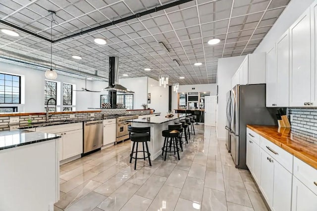 11059 Gold Seal Way, Urbana, NY 14840 - kitchen featuring stainless steel appliances, a spacious island, a breakfast bar, wall chimney range hood, and white cabinetry