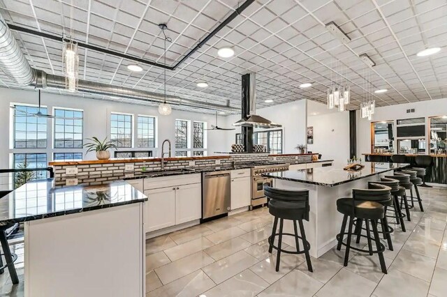 11059 Gold Seal Way, Urbana, NY 14840 - kitchen featuring stainless steel appliances, a breakfast bar, a spacious island, wall chimney range hood, and white cabinetry