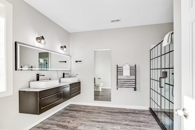 11059 Gold Seal Way, Urbana, NY 14840 - full bathroom with double vanity, wood finished floors, a shower with shower door, and a towel warmer