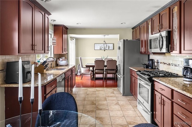79 Hemlock Dr, West Seneca, NY 14224 - kitchen featuring appliances with stainless steel finishes, light stone counters, decorative light fixtures, tasteful backsplash, and a chandelier