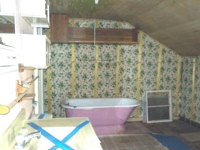 1140 N Main St, Arcadia, NY 14513 - bathroom featuring vaulted ceiling, a soaking tub, and wallpapered walls