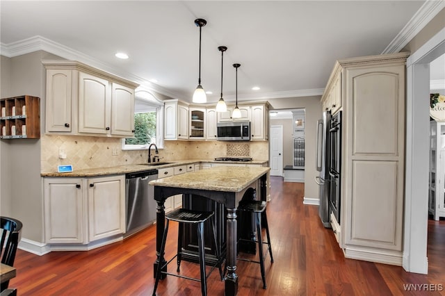 9210 Via Cimato Dr, Clarence, NY 14032 - kitchen featuring appliances with stainless steel finishes, cream cabinets, a kitchen island, light stone countertops, and recessed lighting