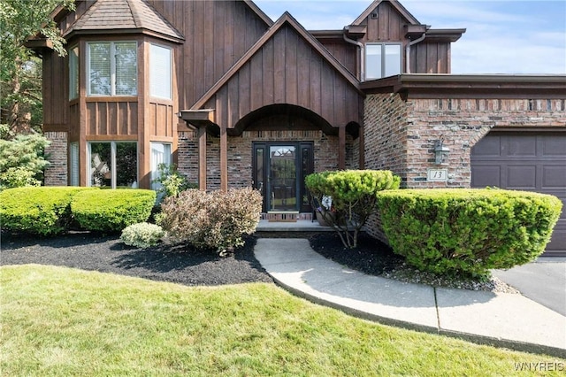 13 Thames Ct, Amherst, NY 14221 - view of exterior entry featuring board and batten siding and a yard