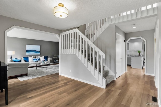 13 Thames Ct, Amherst, NY 14221 - stairway featuring wood finished floors, a textured ceiling, and arched walkways