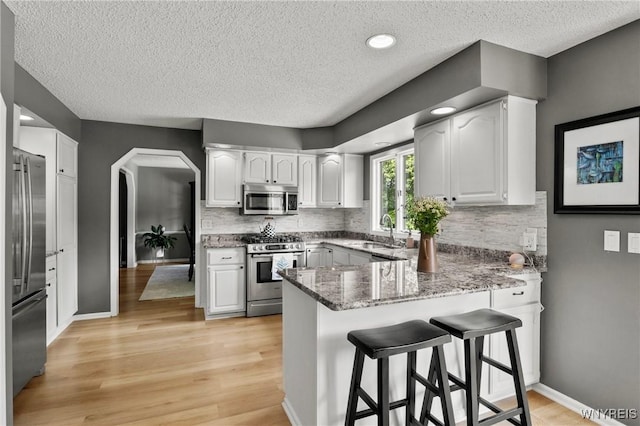 13 Thames Ct, Amherst, NY 14221 - kitchen with stainless steel appliances, a peninsula, a textured ceiling, tasteful backsplash, and stone counters