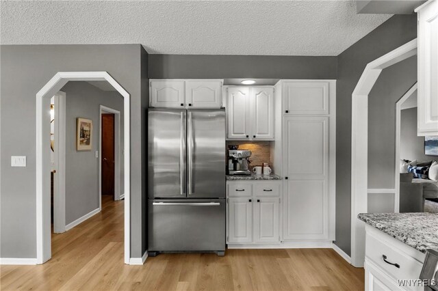 13 Thames Ct, Amherst, NY 14221 - kitchen with freestanding refrigerator, light wood finished floors, white cabinets, light stone countertops, and a textured ceiling