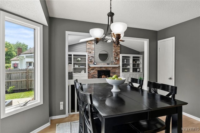 13 Thames Ct, Amherst, NY 14221 - dining area featuring a fireplace, light wood-type flooring, a textured ceiling, and a chandelier