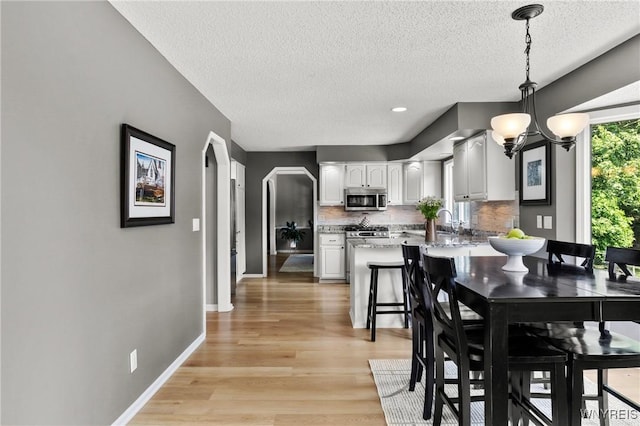 13 Thames Ct, Amherst, NY 14221 - dining area with a textured ceiling, light wood-style floors, and arched walkways