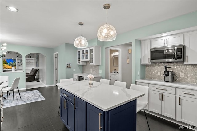 5103 Eastbrooke Pl, Clarence, NY 14221 - kitchen with stainless steel microwave, a chandelier, white cabinets, decorative backsplash, and blue cabinets
