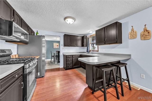 295 Continental Dr, Lockport City, NY 14094 - kitchen featuring appliances with stainless steel finishes, light wood-style floors, a peninsula, a textured ceiling, and light countertops