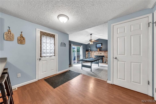 295 Continental Dr, Lockport City, NY 14094 - foyer with a brick fireplace, ceiling fan, wood finished floors, a textured ceiling, and vaulted ceiling