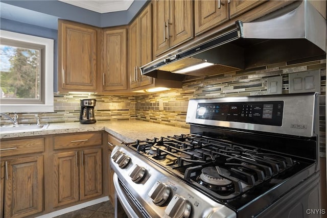 129 Butternut Dr, Dewitt, NY 13214 - kitchen featuring gas range, under cabinet range hood, brown cabinets, backsplash, and crown molding