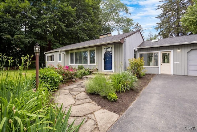 129 Butternut Dr, Dewitt, NY 13214 - view of front facade with driveway, a chimney, and roof with shingles