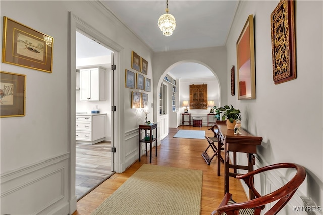 33 Gates Cir Unit 6B, Buffalo, NY 14222 - hallway featuring arched walkways, light wood-type flooring, a chandelier, and crown molding