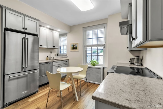33 Gates Cir Unit 6B, Buffalo, NY 14222 - kitchen featuring appliances with stainless steel finishes, light wood-style floors, exhaust hood, radiator heating unit, and gray cabinets