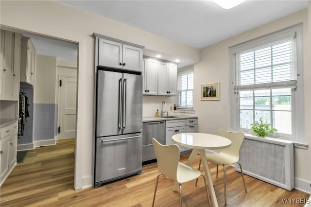 33 Gates Cir Unit 6B, Buffalo, NY 14222 - kitchen featuring appliances with stainless steel finishes, radiator heating unit, light wood-style flooring, and light countertops