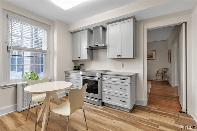 33 Gates Cir Unit 6B, Buffalo, NY 14222 - kitchen featuring stainless steel electric range, wall chimney exhaust hood, radiator, light wood-style floors, and gray cabinetry