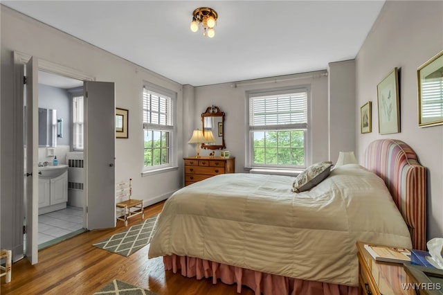 33 Gates Cir Unit 6B, Buffalo, NY 14222 - bedroom featuring multiple windows, radiator, wood finished floors, and connected bathroom