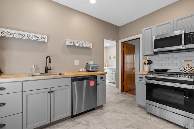 133 Bryant Ave, Syracuse, NY 13204 - kitchen featuring appliances with stainless steel finishes, decorative backsplash, gray cabinetry, butcher block counters, and light marble finish flooring