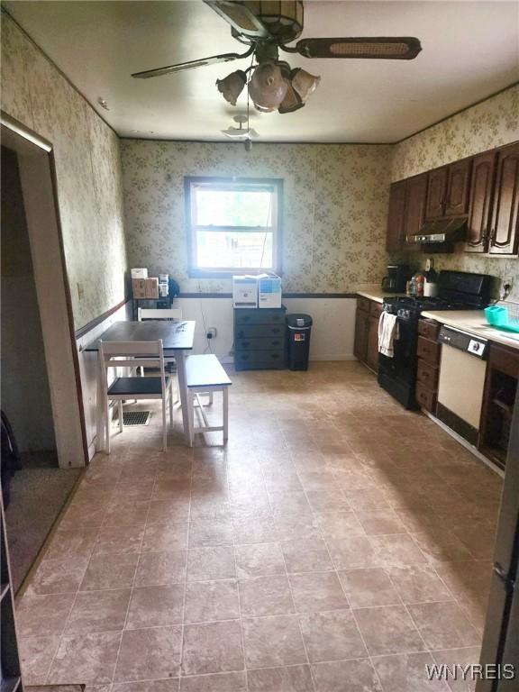 914 S Main St, Shelby, NY 14103 - kitchen featuring black range, wallpapered walls, under cabinet range hood, ceiling fan, and white dishwasher