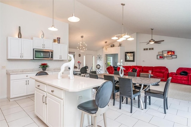 8 Brongo Ln, Gates, NY 14559 - kitchen with stainless steel microwave, open floor plan, light tile patterned floors, light countertops, and high vaulted ceiling