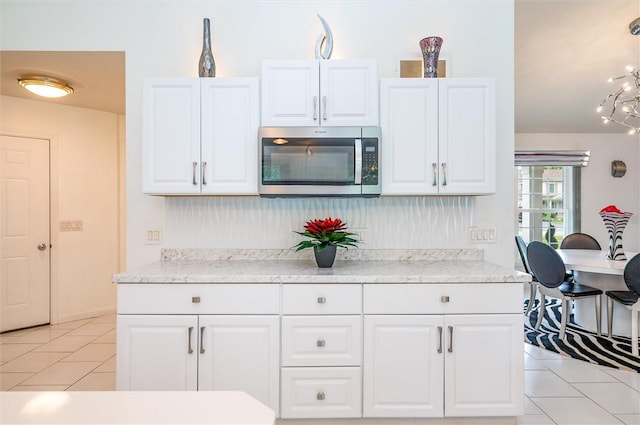 8 Brongo Ln, Gates, NY 14559 - kitchen with stainless steel microwave, light tile patterned floors, white cabinets, decorative backsplash, and light stone counters