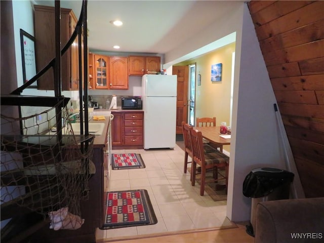 8211 Elmwood Dr, Rushford, NY 14717 - kitchen with freestanding refrigerator, black microwave, brown cabinetry, light tile patterned floors, and recessed lighting