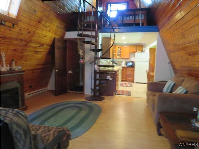 8211 Elmwood Dr, Rushford, NY 14717 - living area with wood walls, stairway, a fireplace, a baseboard heating unit, and a towering ceiling
