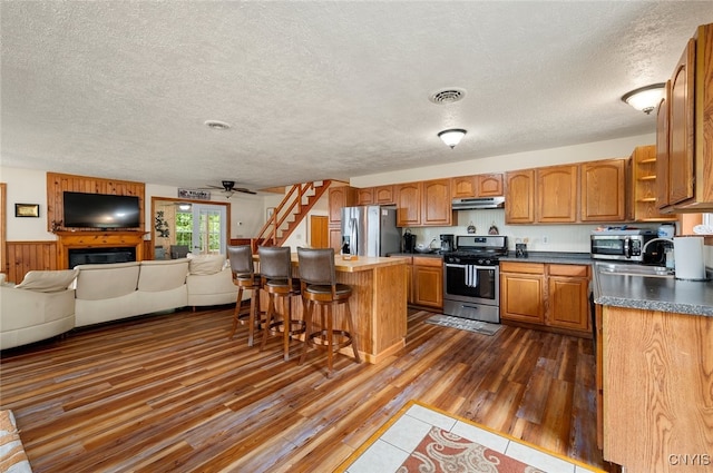 224 Macarthur Rd, Russia, NY 13324 - kitchen with stainless steel appliances, under cabinet range hood, open floor plan, a textured ceiling, and a kitchen bar