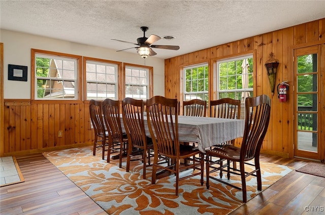 224 Macarthur Rd, Russia, NY 13324 - dining area with wood-type flooring, wood walls, a ceiling fan, a textured ceiling, and wainscoting