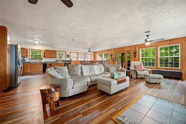 224 Macarthur Rd, Russia, NY 13324 - living room with a ceiling fan, hardwood / wood-style floors, a textured ceiling, and wood walls