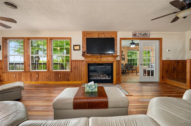 224 Macarthur Rd, Russia, NY 13324 - living area featuring ceiling fan, a textured ceiling, wainscoting, wooden walls, and wood-type flooring