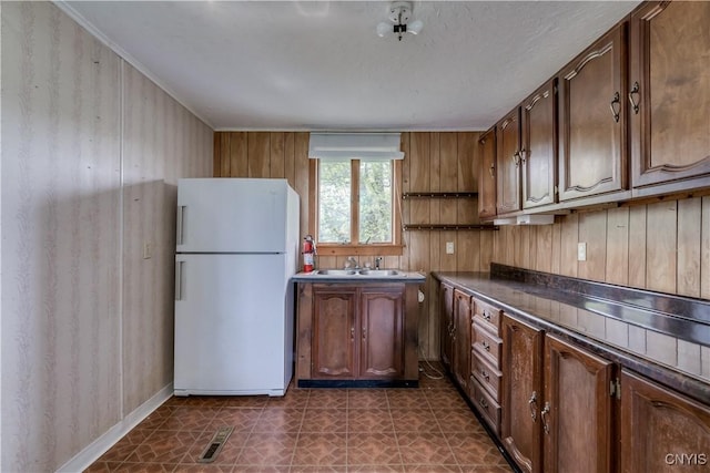 12324 US Route 11, Adams, NY 13606 - kitchen featuring freestanding refrigerator, dark countertops, wood walls, and dark flooring
