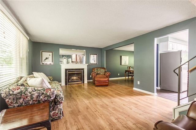 218 Fox Hall Dr, Irondequoit, NY 14609 - living area with healthy amount of natural light, light wood-style flooring, a glass covered fireplace, stairs, and a textured ceiling