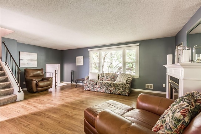 218 Fox Hall Dr, Irondequoit, NY 14609 - living area featuring a textured ceiling, wood finished floors, stairway, and a glass covered fireplace