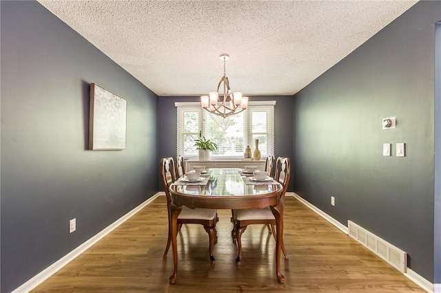 218 Fox Hall Dr, Irondequoit, NY 14609 - dining space featuring a chandelier, a textured ceiling, and wood finished floors