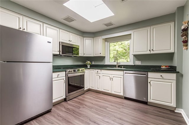 218 Fox Hall Dr, Irondequoit, NY 14609 - kitchen featuring appliances with stainless steel finishes, dark countertops, white cabinetry, and light wood finished floors