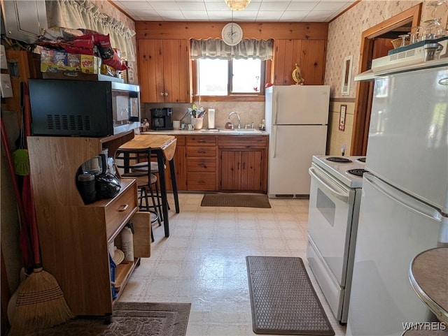 10337 Chaffee Ln, Yates, NY 14098 - kitchen with white appliances, light flooring, under cabinet range hood, brown cabinetry, and wooden walls