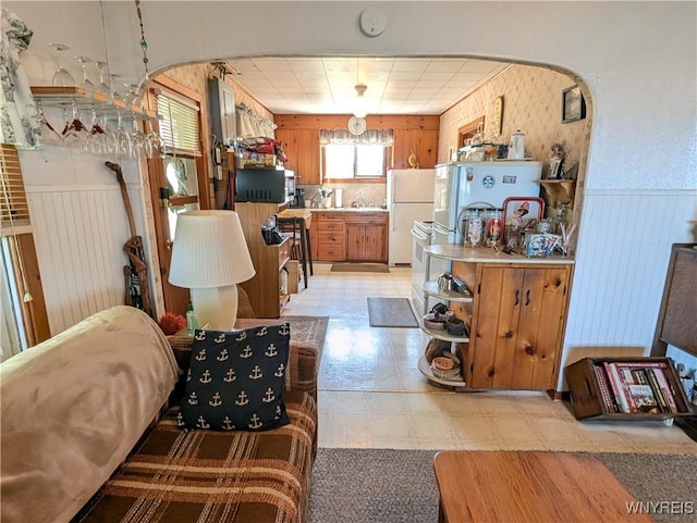 10337 Chaffee Ln, Yates, NY 14098 - kitchen featuring freestanding refrigerator, arched walkways, wainscoting, stainless steel microwave, and wood walls