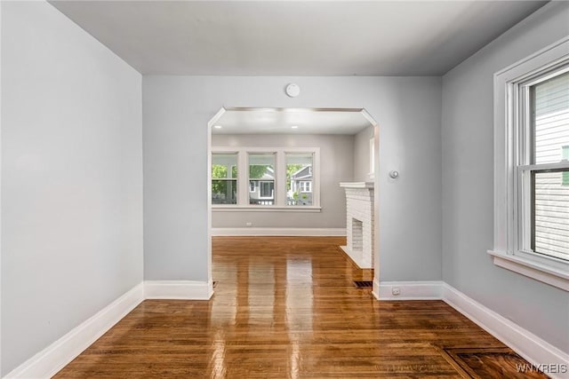 717 Lasalle Ave, Buffalo, NY 14215 - unfurnished living room with wood finished floors, a brick fireplace, and arched walkways