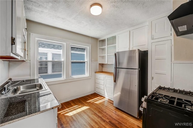717 Lasalle Ave, Buffalo, NY 14215 - kitchen with freestanding refrigerator, range with gas stovetop, range hood, light wood-type flooring, and white cabinetry