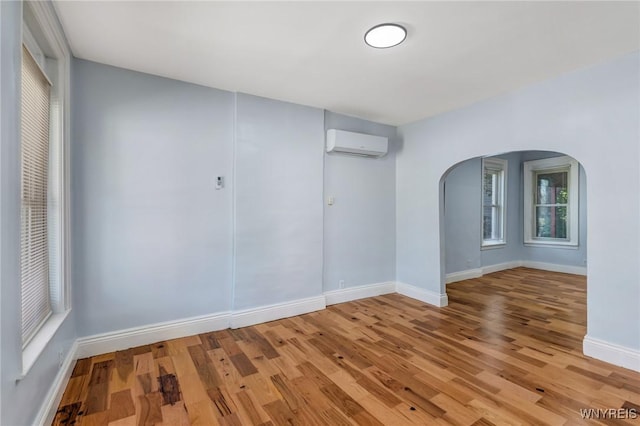 152 Mulberry St, Buffalo, NY 14204 - empty room featuring a wall mounted air conditioner, arched walkways, and light wood-type flooring