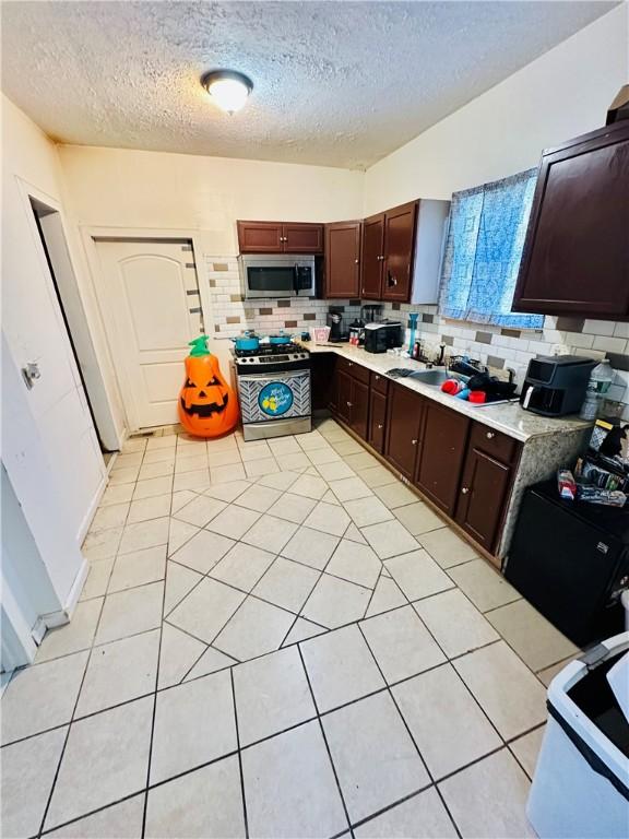 26 Kohlman St, Rochester, NY 14621 - kitchen with appliances with stainless steel finishes, a textured ceiling, backsplash, light countertops, and light tile patterned floors