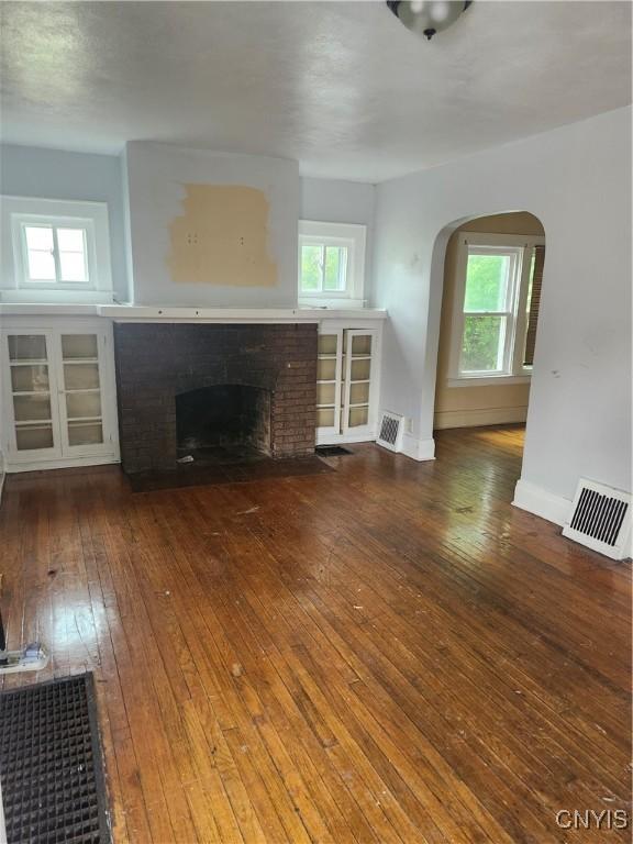 609 W Colvin St, Syracuse, NY 13205 - unfurnished living room featuring arched walkways, a brick fireplace, hardwood / wood-style flooring, and healthy amount of natural light