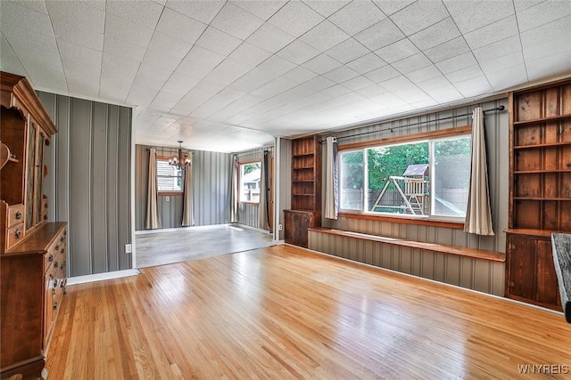 218 Hamilton Dr, Amherst, NY 14226 - empty room featuring a chandelier, built in shelves, wood finished floors, plenty of natural light, and wood walls