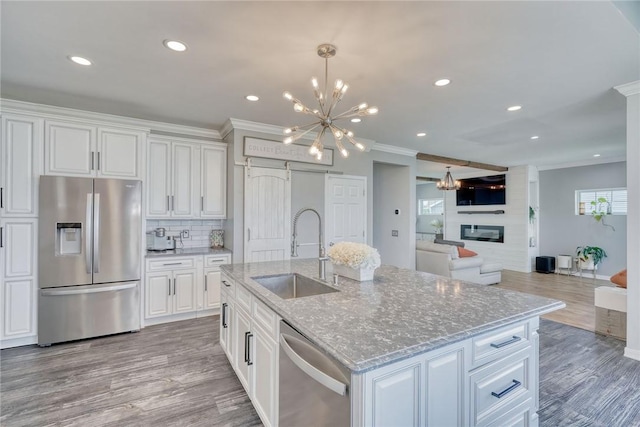 28 Blaydon Loop, Henrietta, NY 14586 - kitchen featuring stainless steel appliances, a chandelier, a fireplace, white cabinets, and ornamental molding