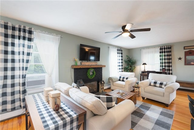 70 E Main St, Avon, NY 14414 - living area featuring wood finished floors, a ceiling fan, a fireplace, baseboard heating, and a baseboard radiator