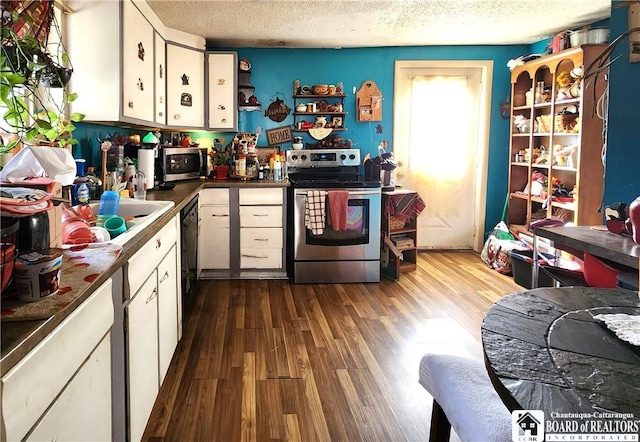 124 Bowen St, Jamestown, NY 14701 - kitchen with stainless steel appliances, a textured ceiling, dark wood-style floors, white cabinetry, and dark countertops